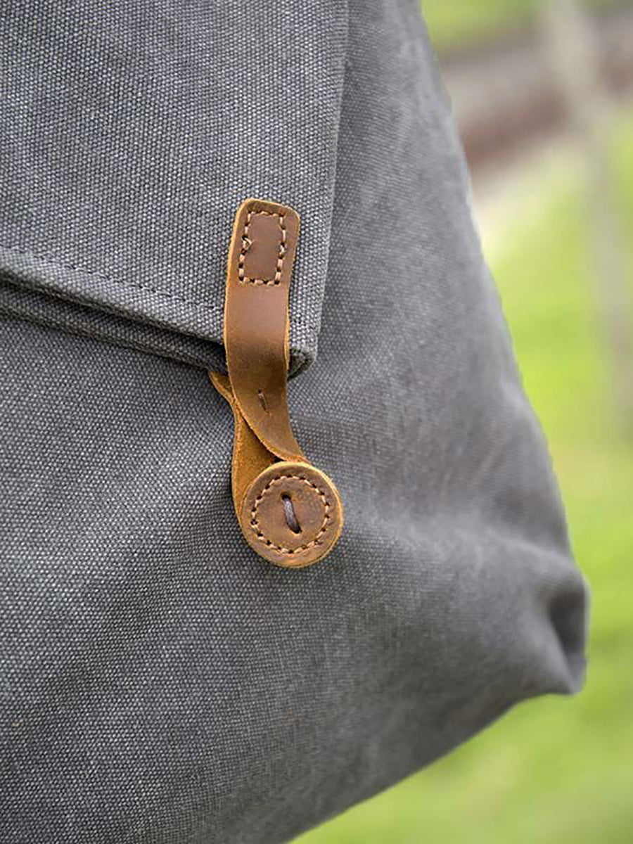 Asymmetrical folded bag with a button, adjustable and stitched